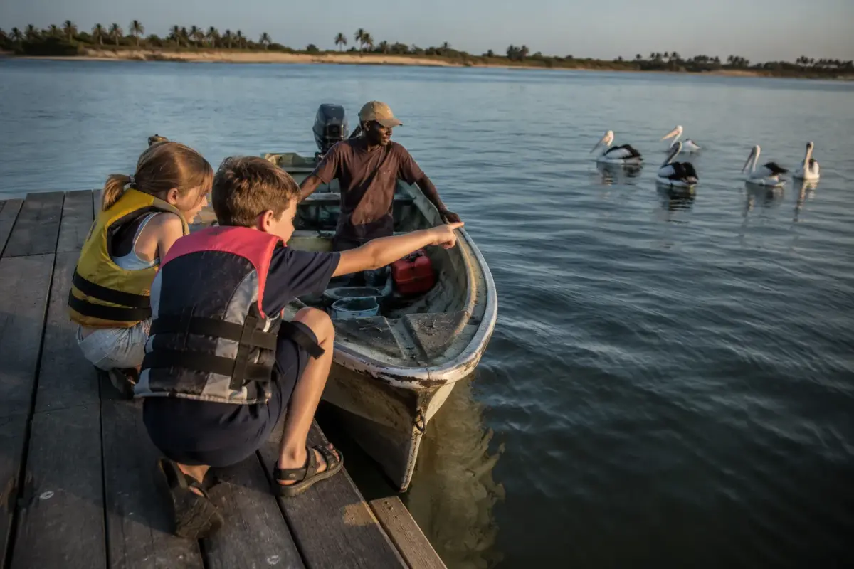 Two children in life jackets watching pelicans from a jetty on the Mussulo lagoon