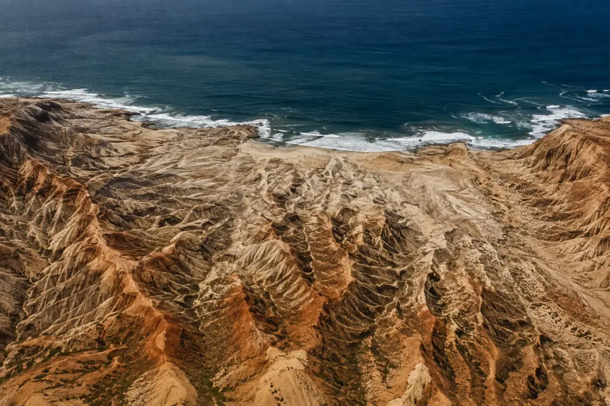 Aerial view of the branching erosion ridges of Miradouro da Lua running down to the Atlantic