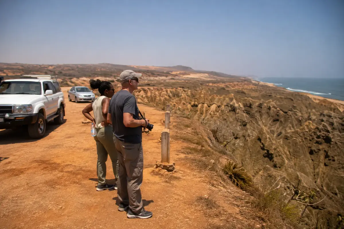 The dusty roadside pull-in at Miradouro da Lua with vehicles parked back from the cliff line