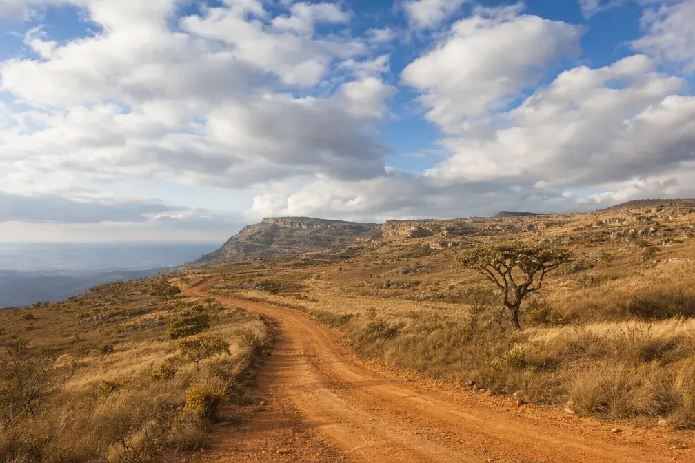 A red-earth track winding through highland grassland northwest of Lubango