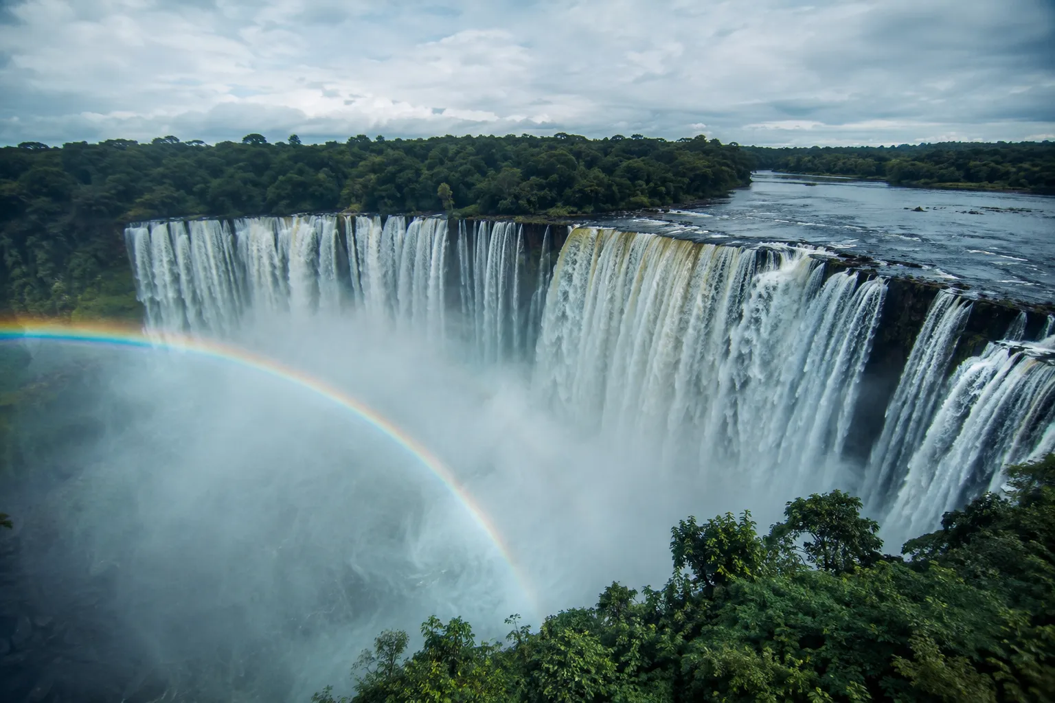 Kalandula Falls in Malanje plunging over a wide horseshoe of dark cliffs into a misty gorge